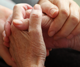 A close-up photo of a younger and older person holding hands.