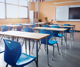 image showing a school classroom with wooden desks and blue chairs