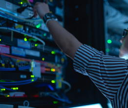 Close-up of an IT worker adjusting a cable in a server room.