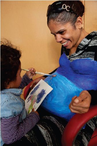 Image of a toddler painting her mother's belly caste. Photograph courtesy of Tobias Titz.