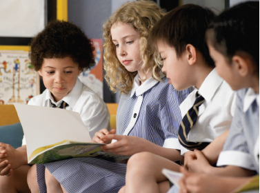 Children in school uniform reading a book together. Photograph courtesy of bikeriderlondon/Shutterstock.