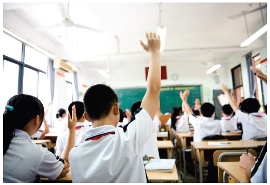 Image of students raising their hands in class - Photograph courtesy of hxdbzxy/Shutterstock.com.