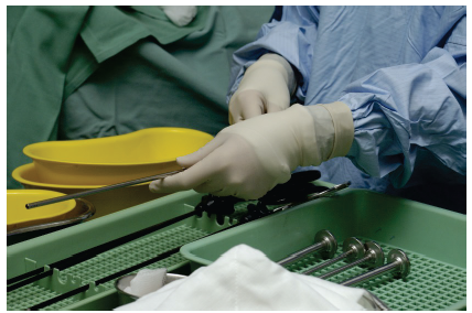 Images shows the instruments for a surgery being handled.