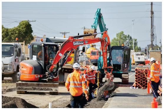 Photo shows construction workers digging up a road