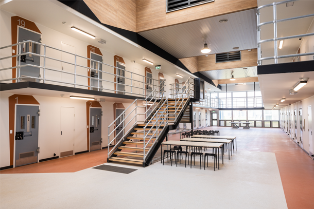 A photo inside a prison in Victoria. There are two rows of prison cells and a staircase. There are tables and chairs next to the staircase.