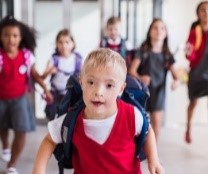 Young student with Down Syndrome running towards viewer, followed by other students.