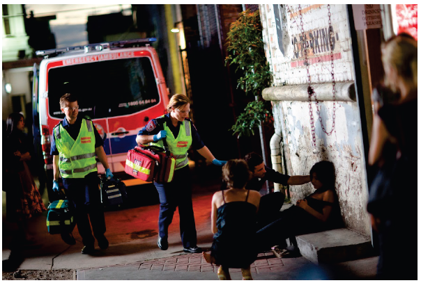 Two paramedics attending a call out in an alleyway at night. They are attending to a girl who is slumped on the floor. Photo courtesy of Ambulance Victoria. 