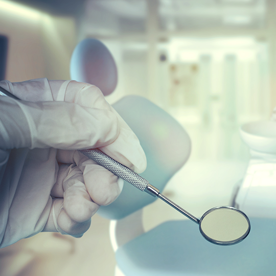 A dentist holding dental instruments. Photo courtesy of Vladislav Max/Shutterstock.com 
