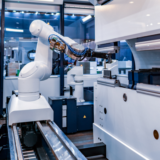 A white robotic arm in a modern industrial lab manufacturing something small in an automated production cell. 