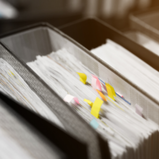 A folder filled with paper with sticky notes.
