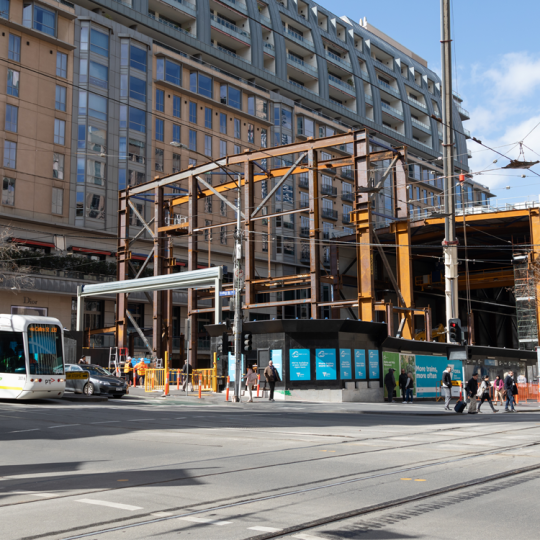 A construction site for the Metro Tunnel Project on Swanston Street. There is a tram next to the construction site.