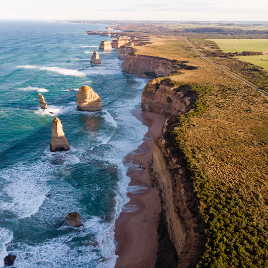 Aerial photo of the Twelve Apostles and coastline on a sunny day.