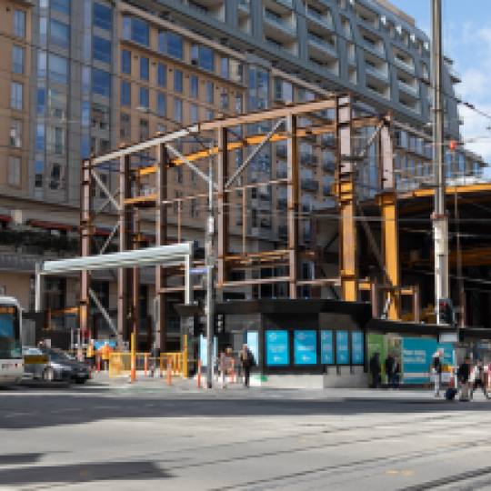 A construction site for the Metro Tunnel Project on Swanston Street. There is a tram next to the construction site.