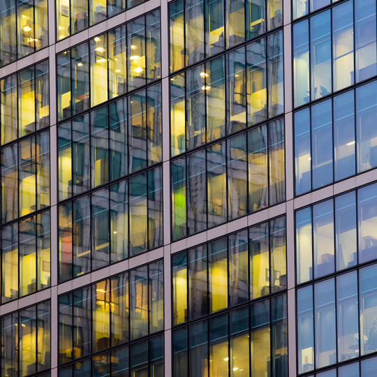 Exterior face of an office building with illuminated windows.