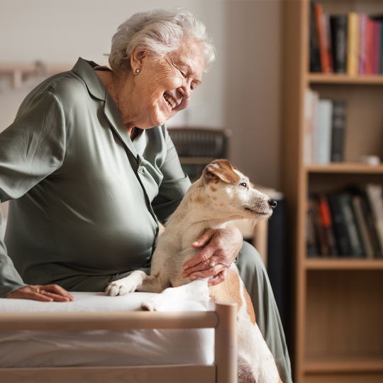 An older woman sitting on a couch with her pet dog.