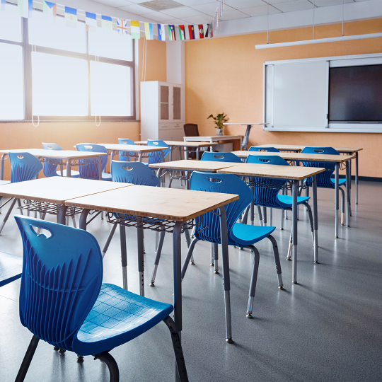 image showing a school classroom with wooden desks and blue chairs