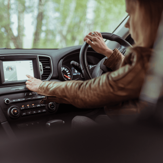 Person looking at and touching a sat nav screen while driving