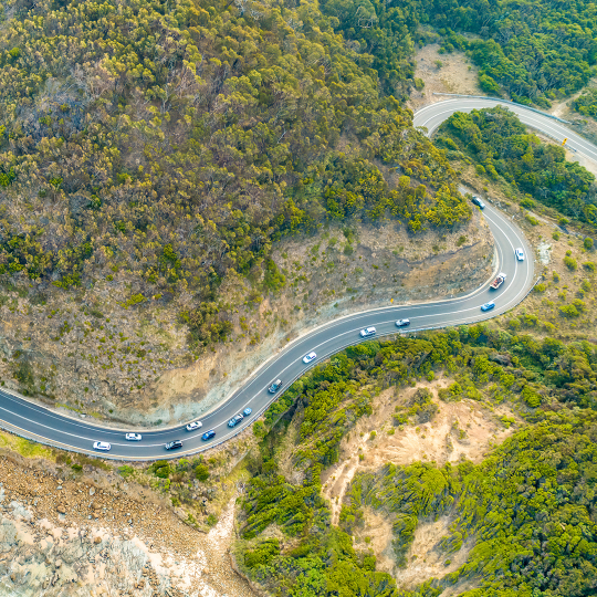 An aerial view of a road winding around wooded hills in Victoria.