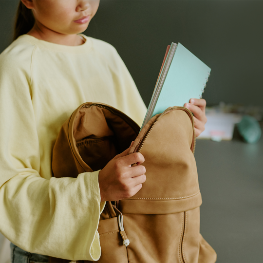 A child taking a notebook out of a backpack.