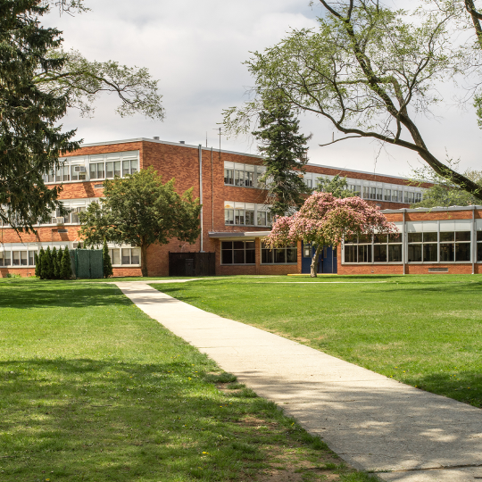 A multistorey brick school building on a sunny day.