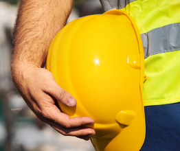 Image shows man holding yellow helmet close up. Photo courtesy of ZoranOrcik/Shutterstock.com