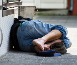 Homeless man sleeping on the street. Photo courtesy of Srdjan Randjelovic/shutterstock.com