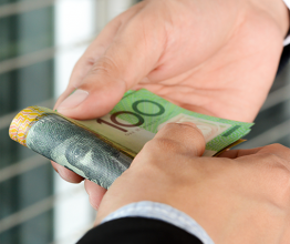 Businessman hands passing money, Australian dollar (AUD) banknotes. Photocourtesy of Atstock Productions/Shutterstock.com