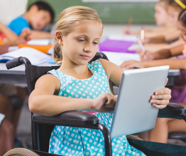 Image shows Disabled schoolgirl using digital tablet in classroom at school. Photo courtesy of wavebreakmedia/Shutterstock.com