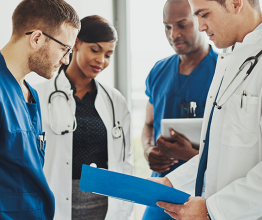 Group of doctors reading a document in meeting room at hospital. Photo courtesy of Uber Images/Shutterstock.com