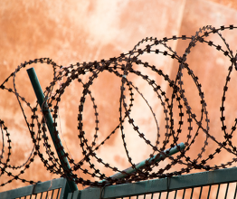Image shows barbed wire fence used for protection in jail. Photo courtesy of Berke/Shutterstock.com
