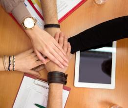 Image shows hands together team unity concept. Photo courtesy of Lucky Business/Shutterstock.com