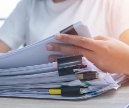 Woman with stack of papers. Photo courtesy of smolaw/shutterstock.com