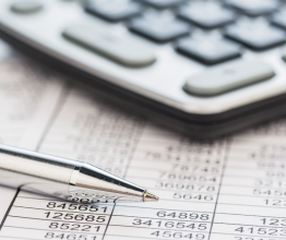 Close up of calculator, pen and financial documents on a desk.