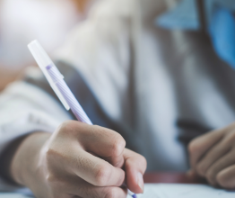 Close-up of a person's hand writing on a piece of paper with a pen.