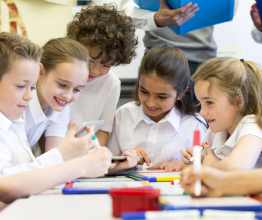 A group of primary school students working together at a table in a classroom.