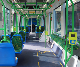Interior of a tram showing the entrance, areas for wheelchair access, and chairs.