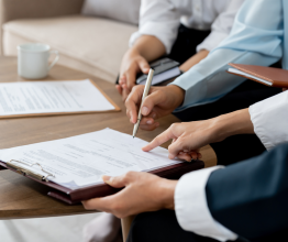 Close up of a three people reviewing a document on a clipboard.