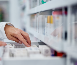 Hands browsing through a drawer of medicines in a pharmaceutical stockroom.