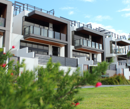A row of newly built townhouses overlooking a park. 