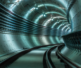 Looking around a curve in a newly built underground rail tunnel.