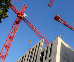Red cranes against a blue sky on a construction site.