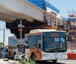 A train replacement bus driving past a level crossing removal construction site.