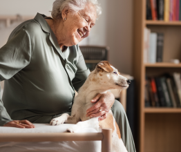 An older woman sitting on a couch with her pet dog.