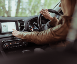 Person looking at and touching a sat nav screen while driving