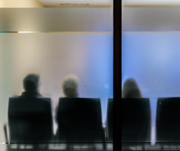 People sitting in a waiting room behind frosted glass
