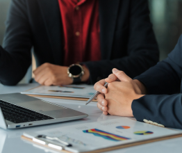 People looking at a laptop with clipboards