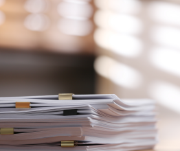 Stack of paper documents on a desk.