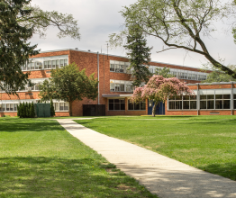 A multistorey brick school building on a sunny day.